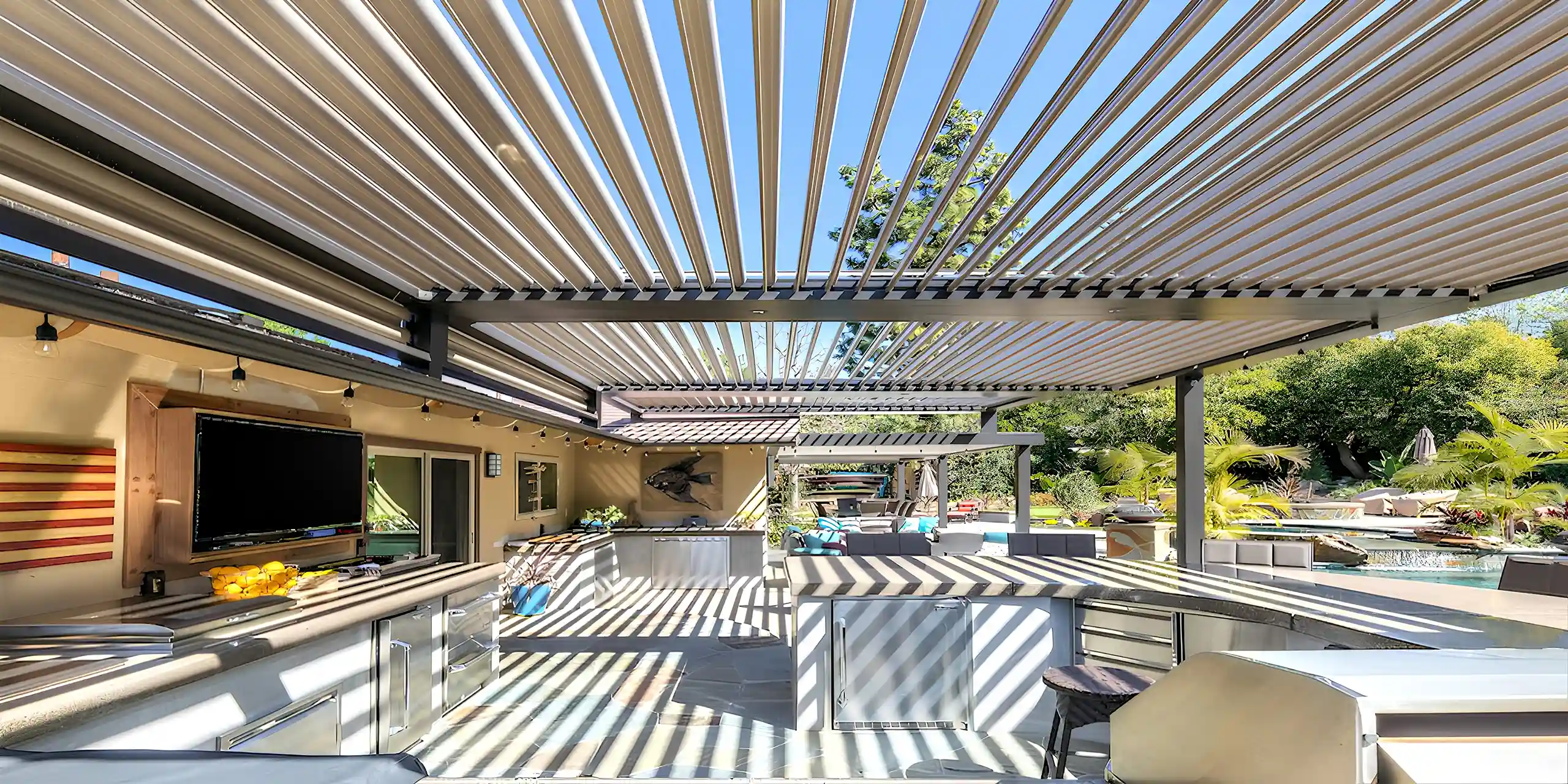 Photo of motorized louvered roof pergola providing cover for outdoor kitchen, dining room, and living room.